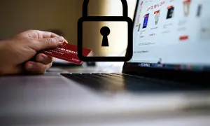Mano con carta di credito davanti a un laptop con lucchetto. Attenzione: sito non sicuro come accedere.