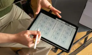 Mani che usano uno stilo su un tablet, mostrando un grafico web con prodotti e offerte.