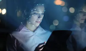 Donna con volto analizzato da rete neurale, tablet in mano. Il phygital significato è qui: fusione tra reale e virtuale.