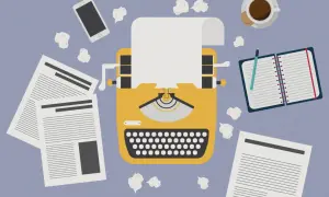 Macchina da scrivere gialla, fogli, smartphone, taccuino e caffè. Un invito a essere creativi, anche quando le idee sembrano finite.