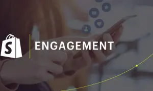 Logo Shopify e parola "ENGAGEMENT" su sfondo sfocato con icone social. Strategie di engagement marketing per far crescere il tuo business.