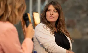Martina Carone, con capelli castani e un cardigan beige, ascolta attentamente durante un'intervista.