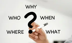 I 5 W del giornalismo: Who, What, When, Where, Why. Una mano tiene una penna, pronta a rispondere alle domande fondamentali.