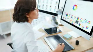 Donna lavora come web editor, usando un tablet grafico e monitor con palette colori.