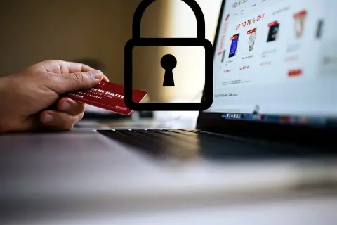 Mano con carta di credito davanti a un laptop con lucchetto. Attenzione: sito non sicuro come accedere.