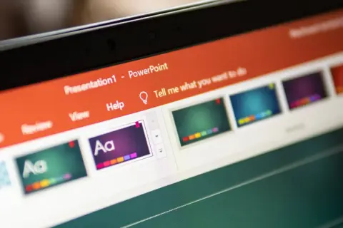 Schermo di un laptop con una presentazione PowerPoint aperta. Si vedono miniature di diapositive colorate e la barra degli strumenti.