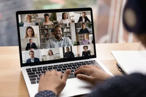 Schermo di un laptop con una videoconferenza in corso, mostrando volti sorridenti di persone che partecipano a eventi digitali.