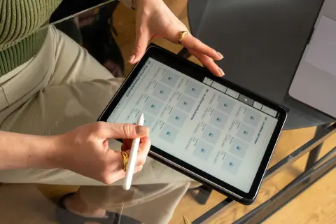 Mani che usano uno stilo su un tablet, mostrando un grafico web con prodotti e offerte.
