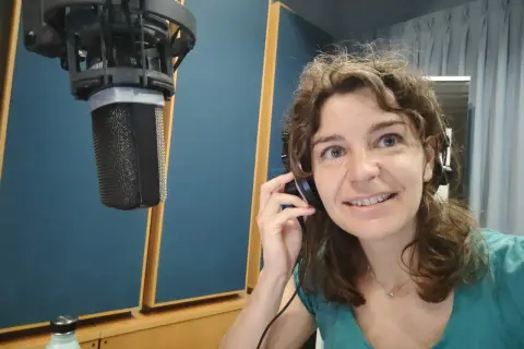 Roberta Fulci in uno studio di registrazione, con cuffie e microfono, pronta per una sessione vocale.