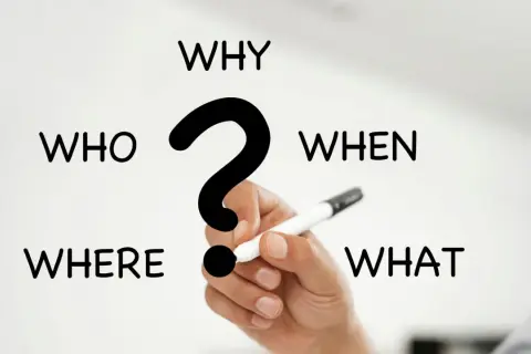 I 5 W del giornalismo: Who, What, When, Where, Why. Una mano tiene una penna, pronta a rispondere alle domande fondamentali.