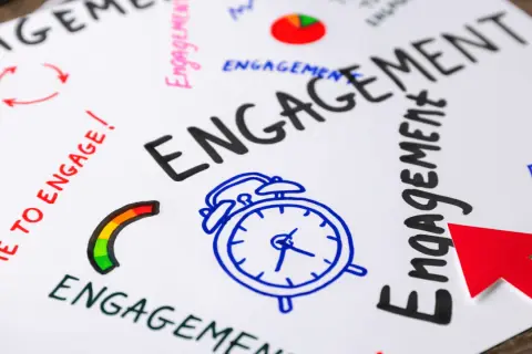 Mappa mentale con la parola "ENGAGEMENT" in grande, circondata da icone e frasi che stimolano l'audience engagement: sveglia, freccia rossa, grafico a torta.
