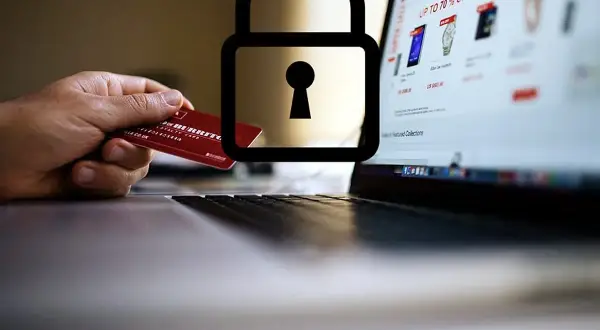 Mano con carta di credito davanti a un laptop con lucchetto. Attenzione: sito non sicuro come accedere.