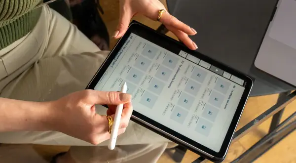 Mani che usano uno stilo su un tablet, mostrando un grafico web con prodotti e offerte.