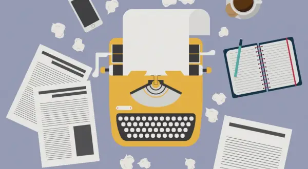 Macchina da scrivere gialla, fogli, smartphone, taccuino e caffè. Un invito a essere creativi, anche quando le idee sembrano finite.