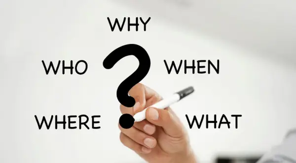I 5 W del giornalismo: Who, What, When, Where, Why. Una mano tiene una penna, pronta a rispondere alle domande fondamentali.