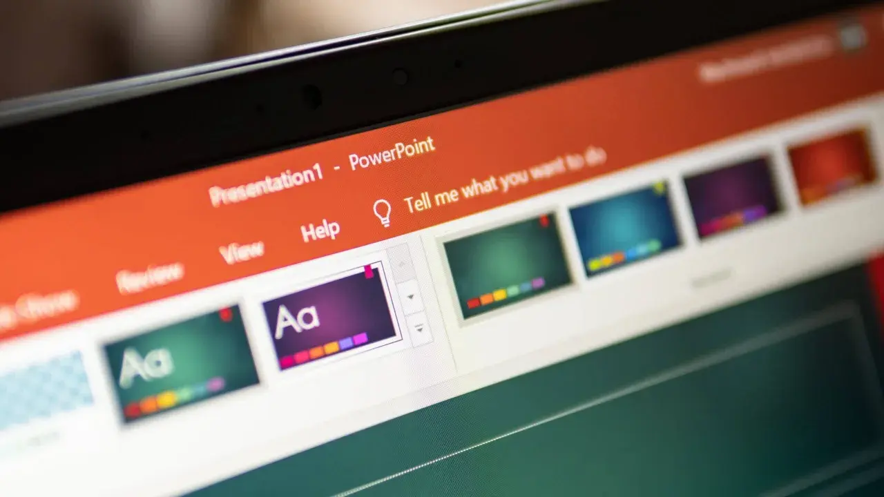 Schermo di un laptop con una presentazione PowerPoint aperta. Si vedono miniature di diapositive colorate e la barra degli strumenti.
