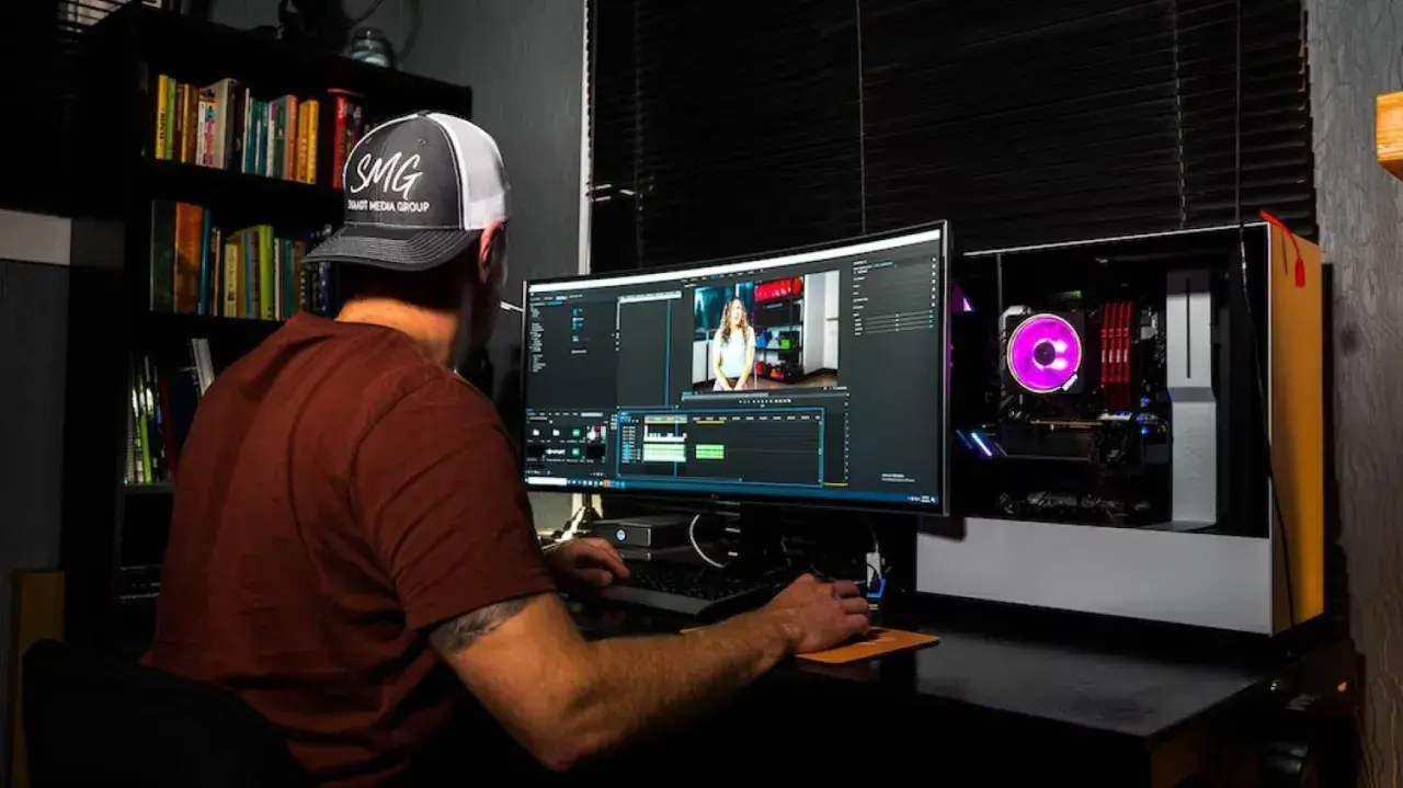Uomo con cappellino SMG impegnato in un corso di editing video, lavora su un computer con software di montaggio.