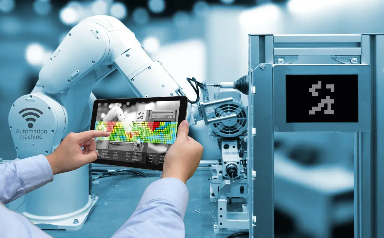 Un braccio robotico e un tablet mostrano l'interfaccia di una macchina automatizzata, illustrando cos'è l'industria 4.0.