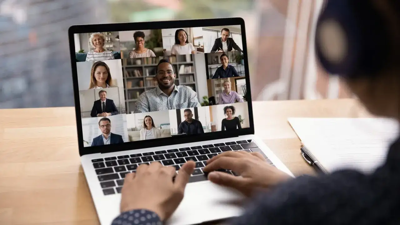 Schermo di un laptop con una videoconferenza in corso, mostrando volti sorridenti di persone che partecipano a eventi digitali.