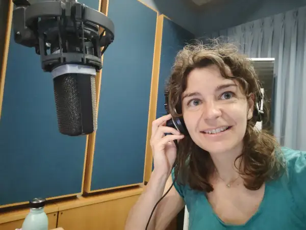 Roberta Fulci in uno studio di registrazione, con cuffie e microfono, pronta per una sessione vocale.