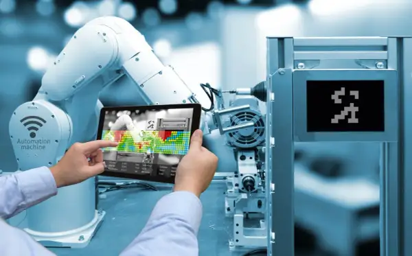 Un braccio robotico e un tablet mostrano l'interfaccia di una macchina automatizzata, illustrando cos'è l'industria 4.0.