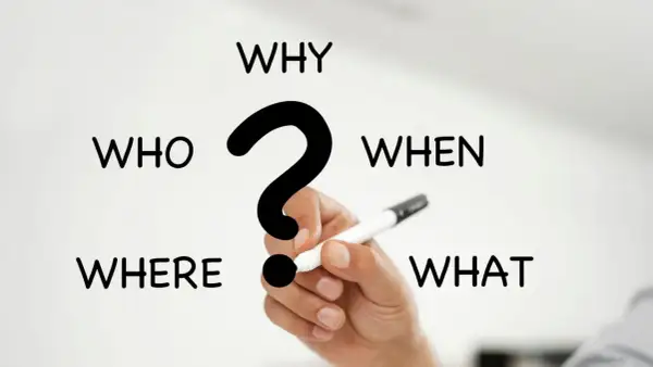 I 5 W del giornalismo: Who, What, When, Where, Why. Una mano tiene una penna, pronta a rispondere alle domande fondamentali.