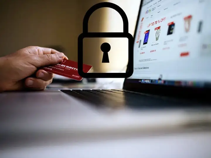 Mano con carta di credito davanti a un laptop con lucchetto. Attenzione: sito non sicuro come accedere.